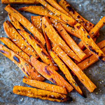 Browned truffle oil sweet potatoes fries on a dark-grey background.