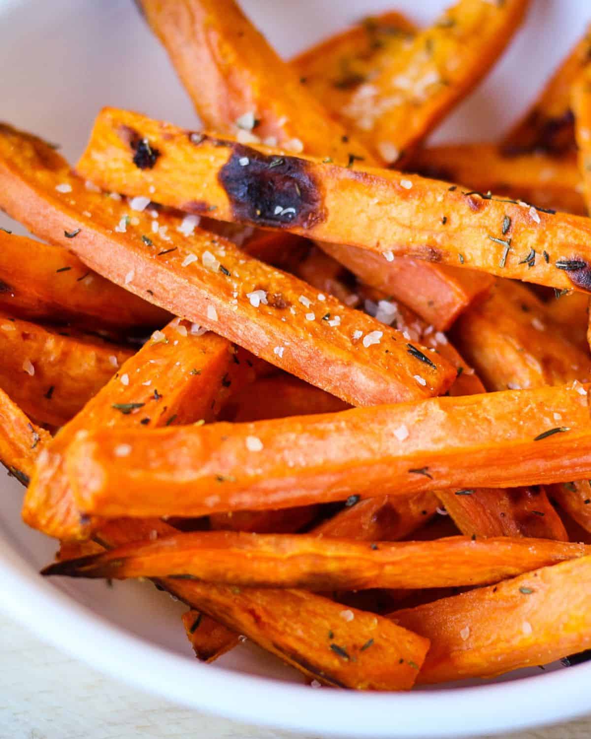 Close-up view of cooked sweet potatoes sprinkled with grated parmesan and salt.