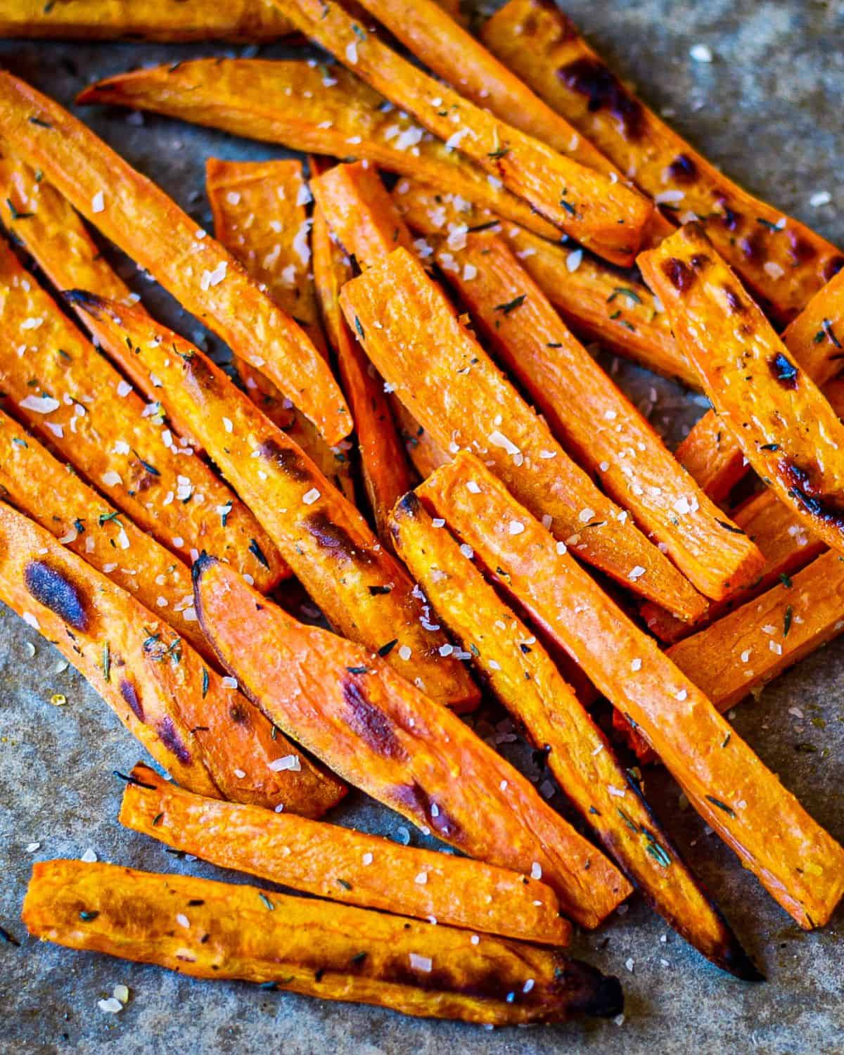 Browned sweet potatoes orange fries on a dark-grey background. 