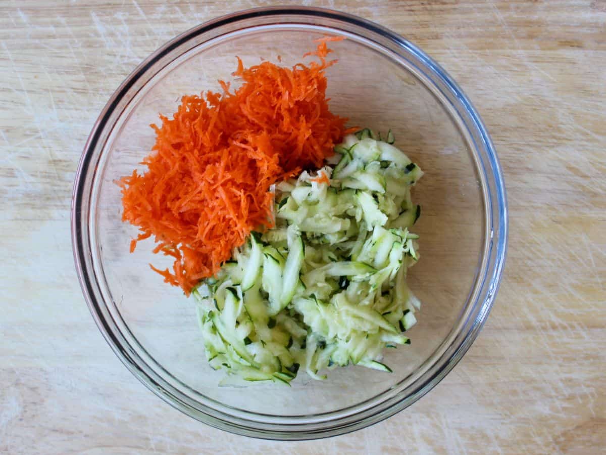 A glass bowl with grated zucchini and carrot.