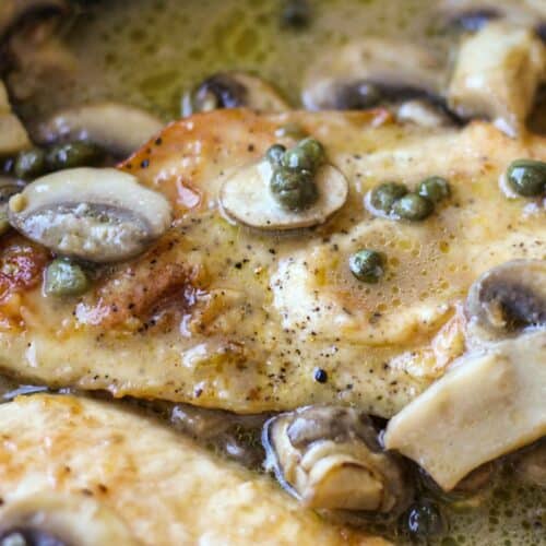 Cooked chicken breasts in sauce with capers and mushrooms.