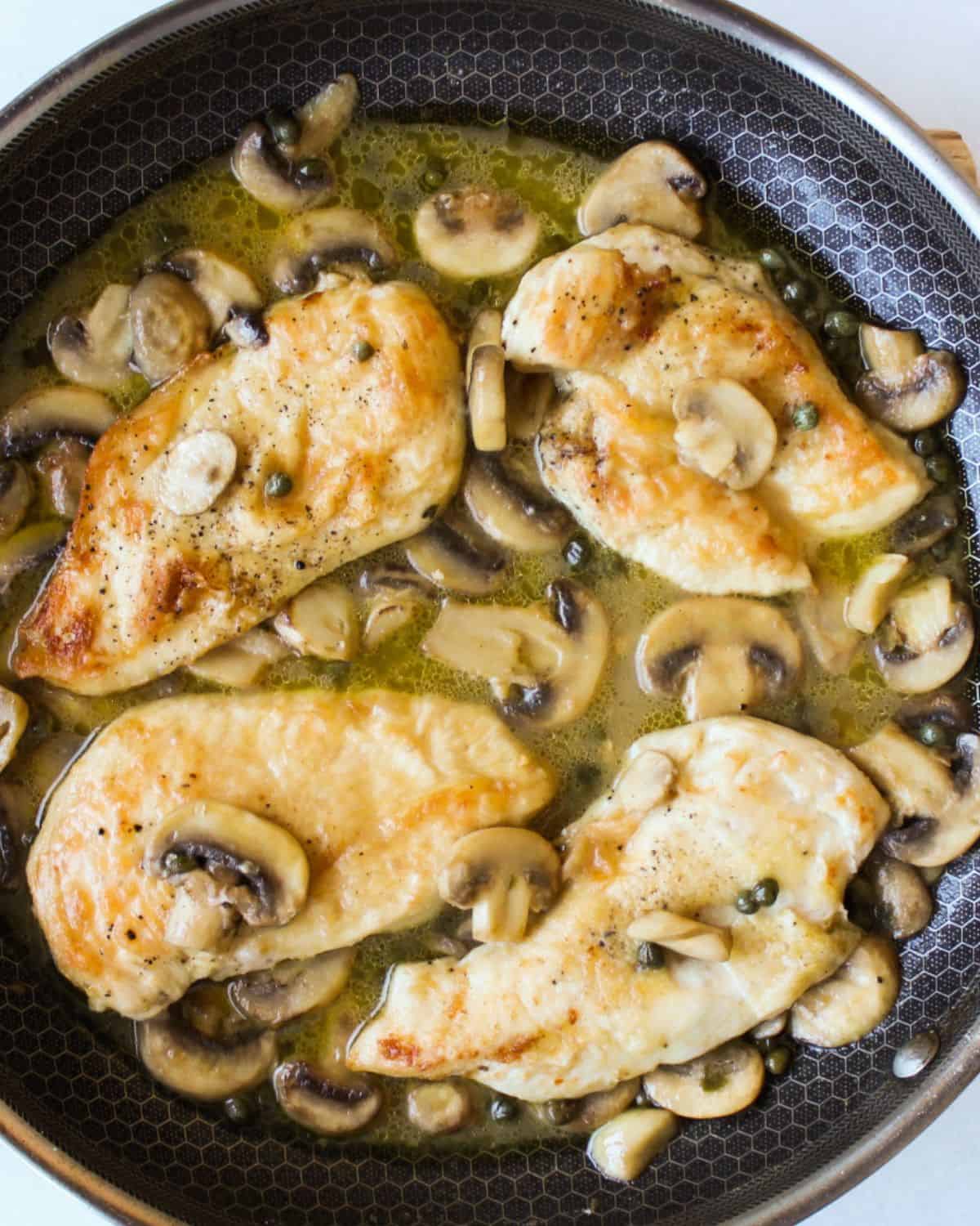 Cooked chicken cutlets are added to the skillet with piccata sauce.