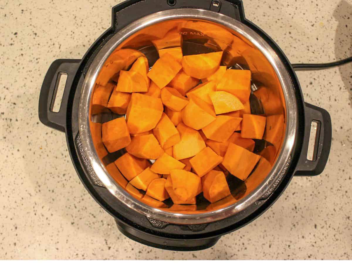 Instant pot filled with cubed raw sweet potatoes.