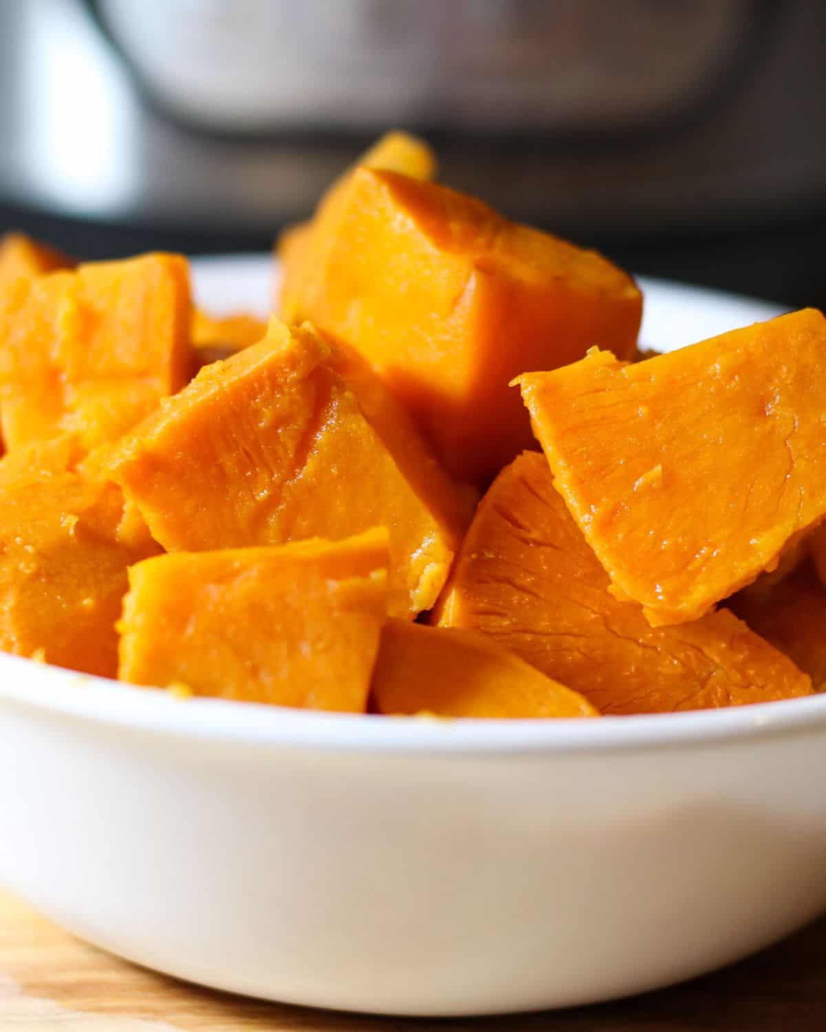 A white bowl with steamed sweet potato cubes.