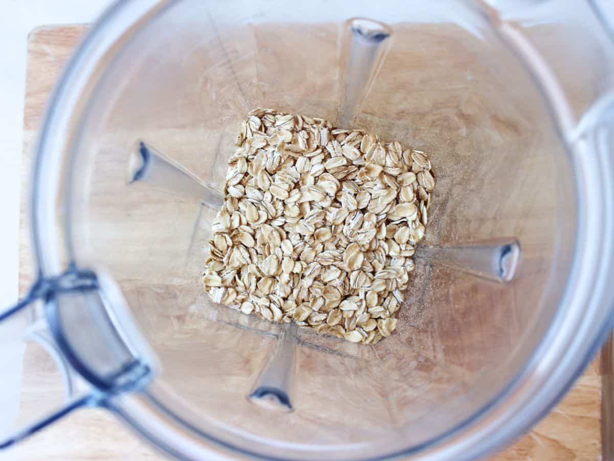 Overhead view of a plastic blender container filled with uncooked oats.
