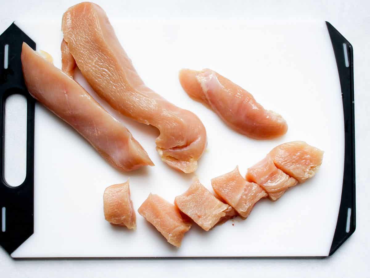 Raw chicken breast cut into strips lengthwise and then into bite-sized pieces.