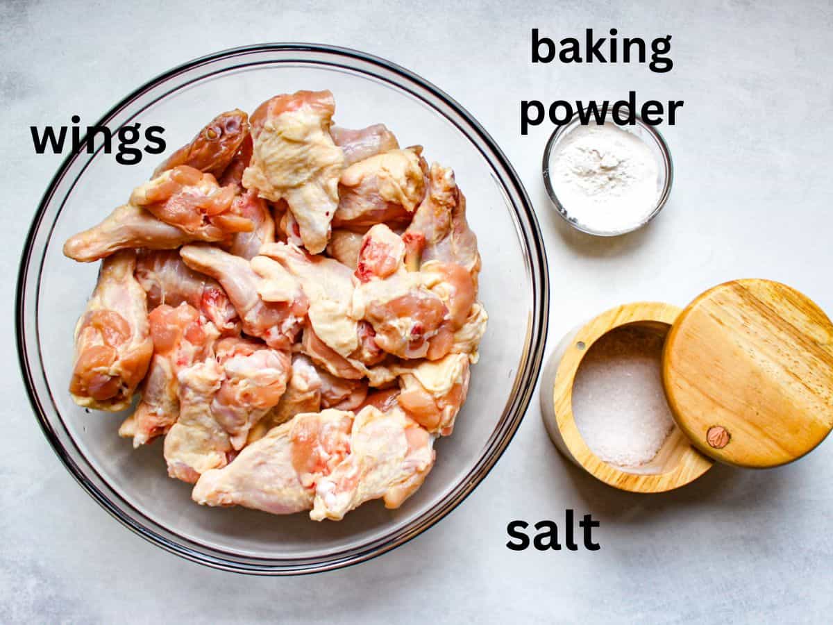 Raw chicken wings, baking powder and salt on a white background.