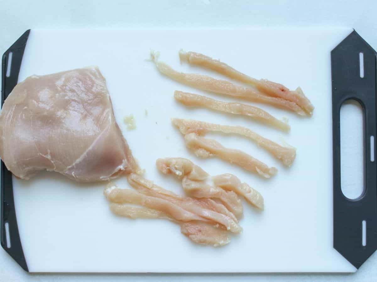 Raw chicken breast cut into thin strips.