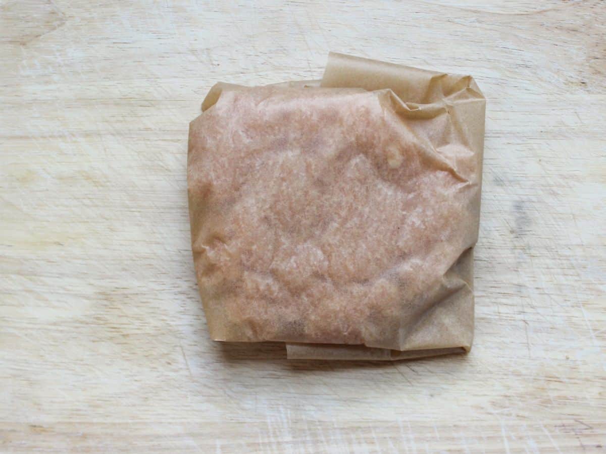 Ground chicken wrapped into a parchment paper and shaped into a square.