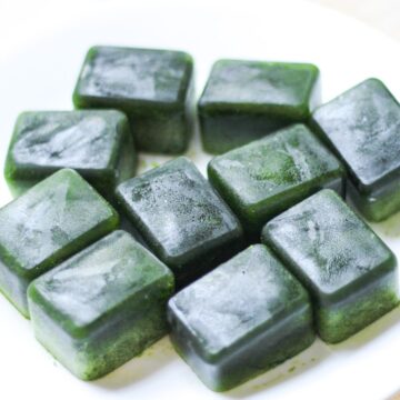 Frozen rectangular spinach cubes on a white plate.
