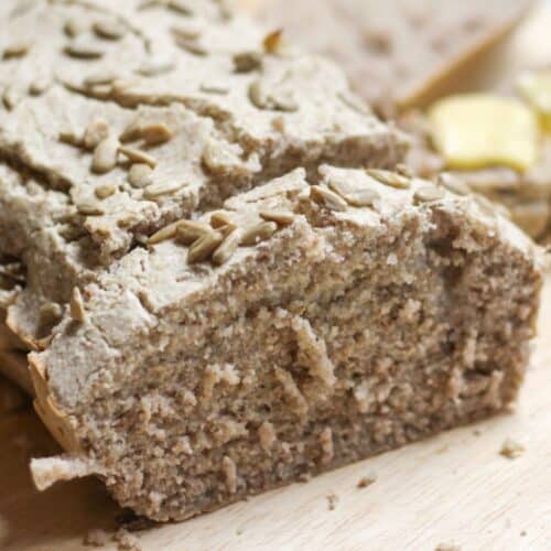 A loaf of gluten-free buckwheat bread sliced on a cutting board.