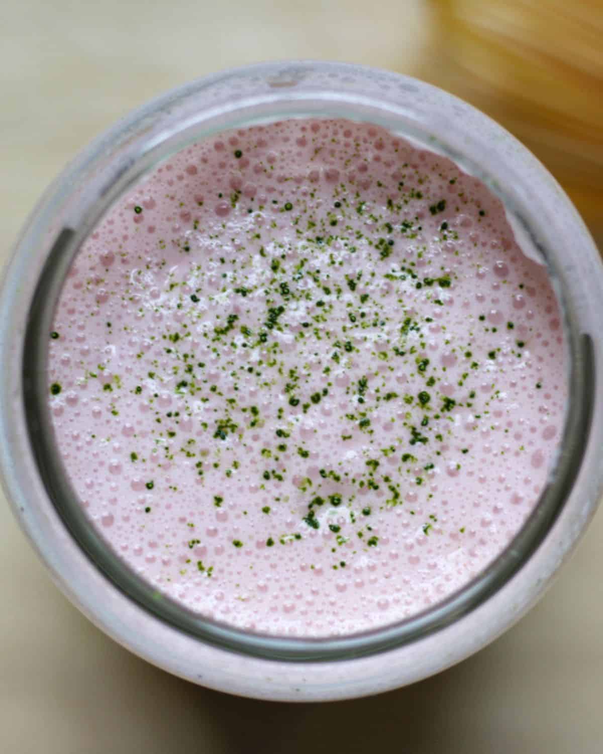 Overhead view of strawberry matcha in a clear glass.