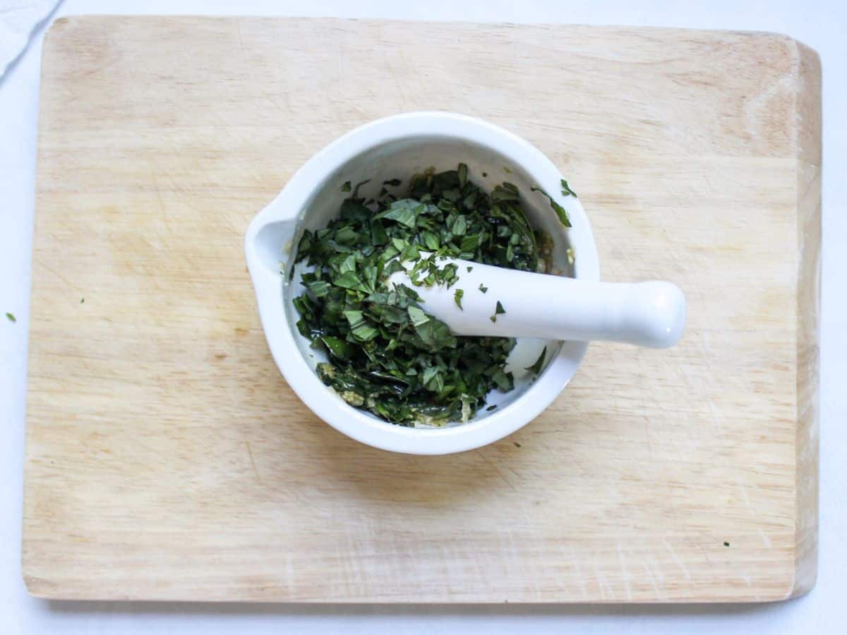 Chopped basil leaves added to the mortar.