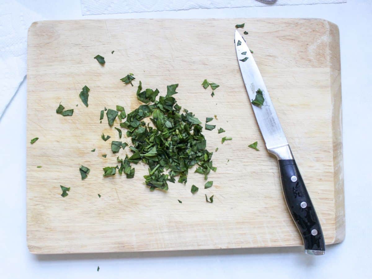 Finely chopped basil leaves on a cutting board.
