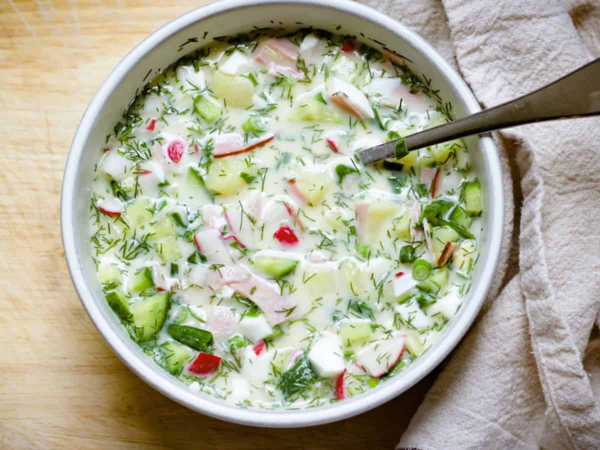 Assembled okroshka soup with added liquid in a bowl.