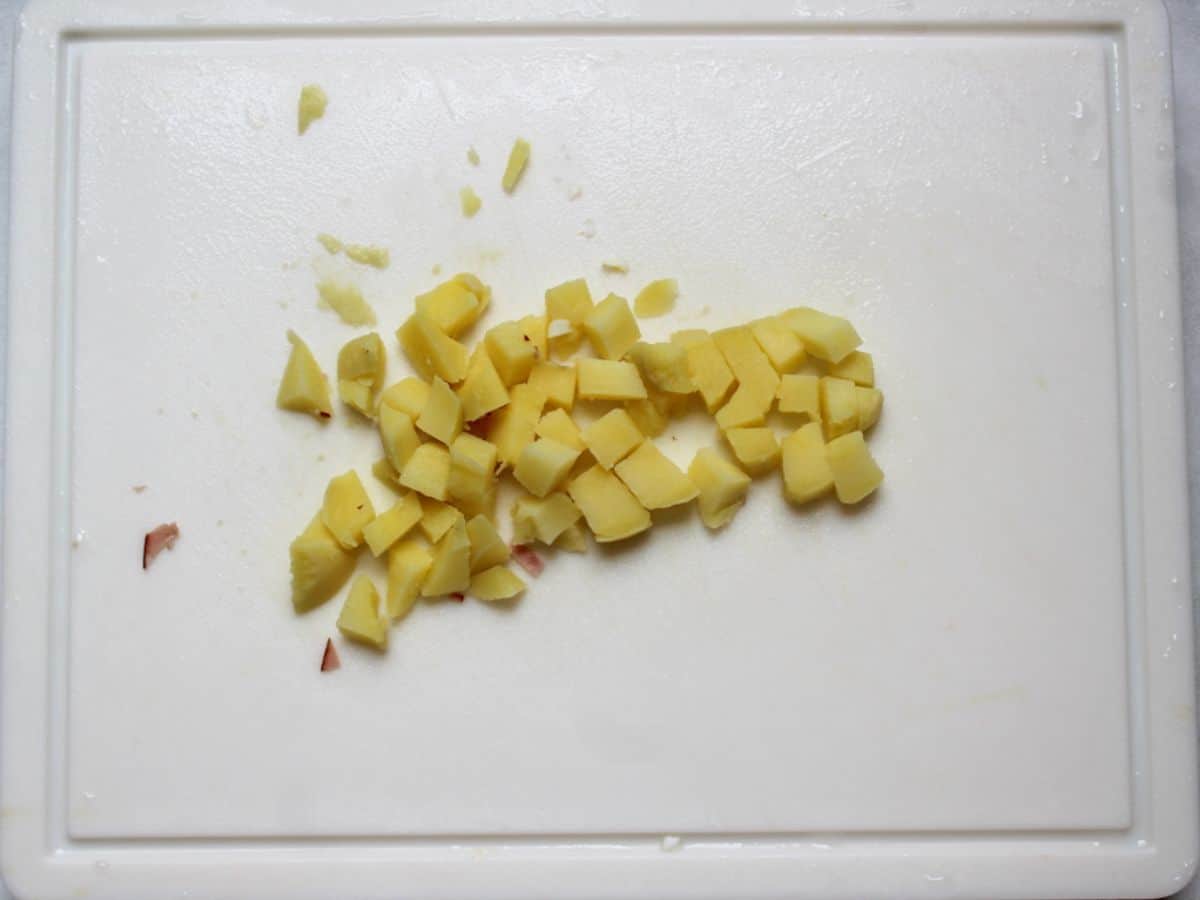 Diced boiled potato on a white cutting board.