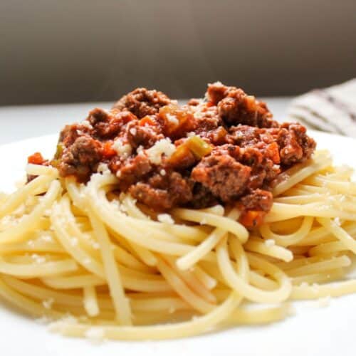 Bolognese meat sauce served over spaghetti , garnished with some grated Parmesan.