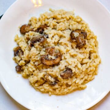 Risotto con funghi served in a white plate.