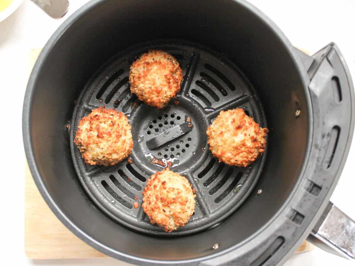 Golden-brown and crispy rice balls in air fryer basket.