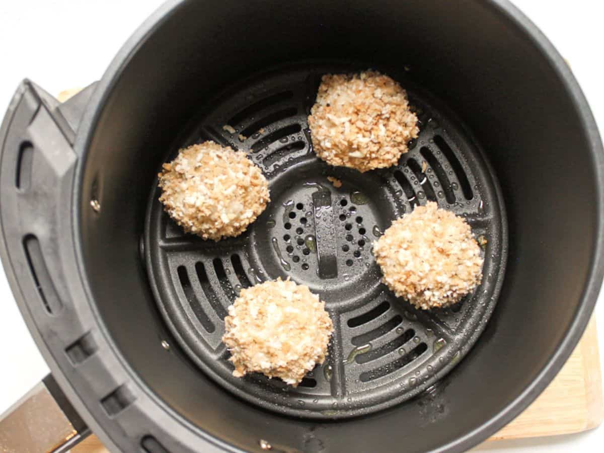 Covered in breadcrumbs risotto balls arranged in air fryer basket.