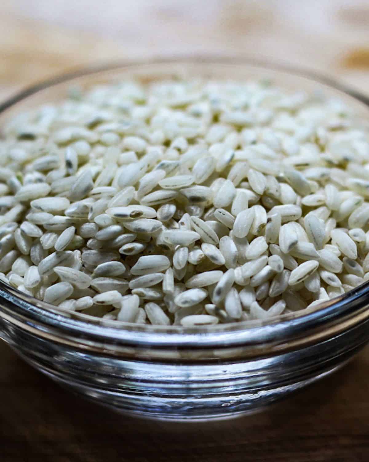 Uncooked Arborio rice in a glass bowl.