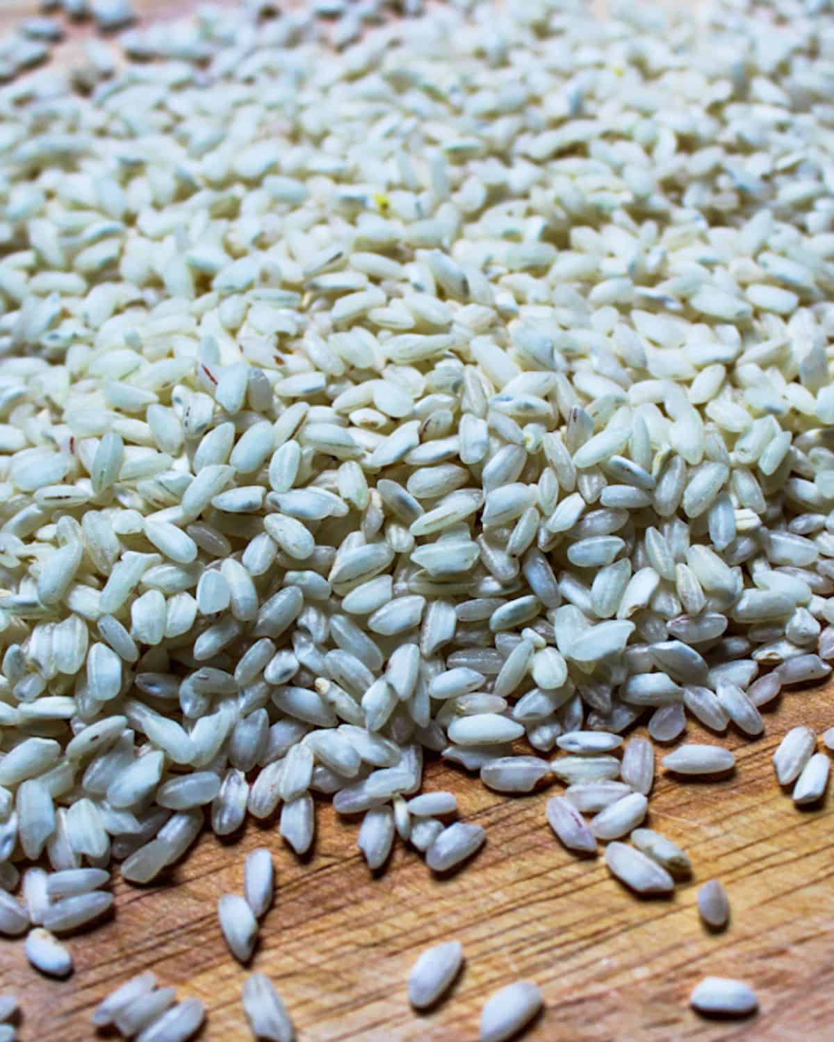 Uncooked rice grains poured on the wooden surface.