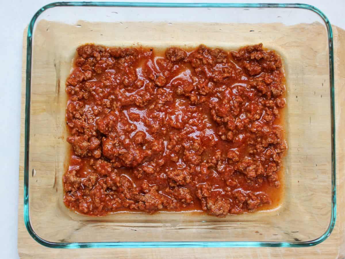 Meat sauce at the bottom of a glass container.