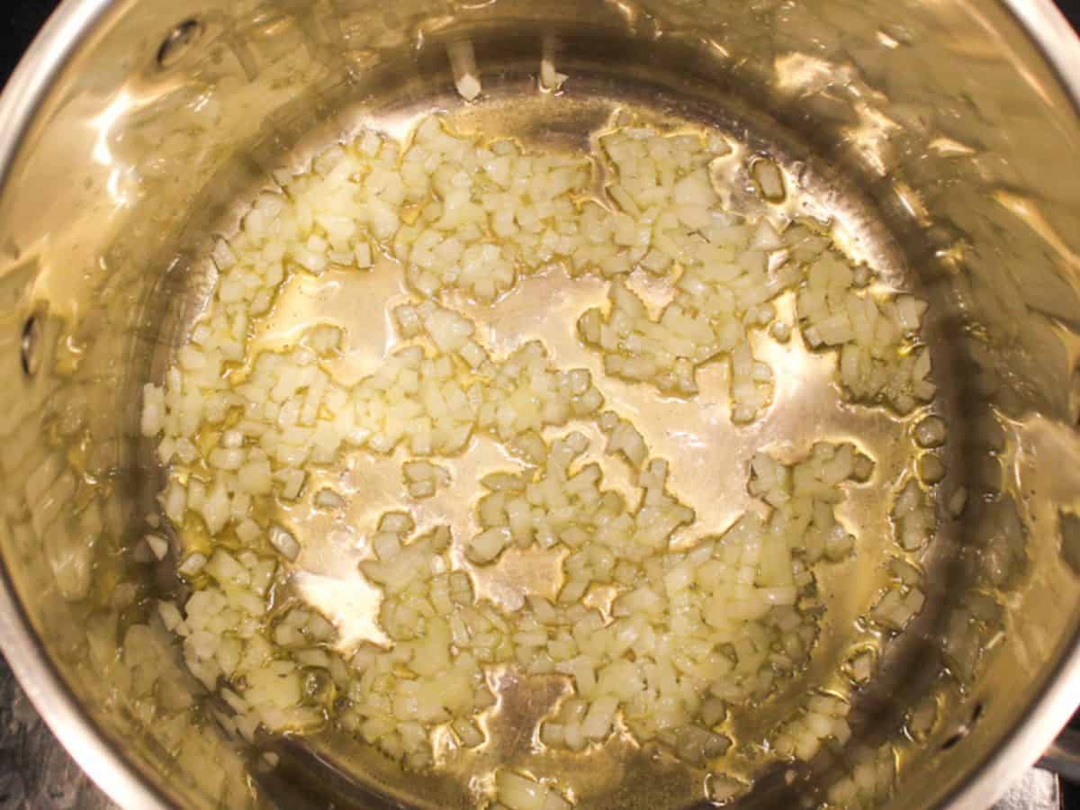 Diced onion cooking in olive oil on a large pot.