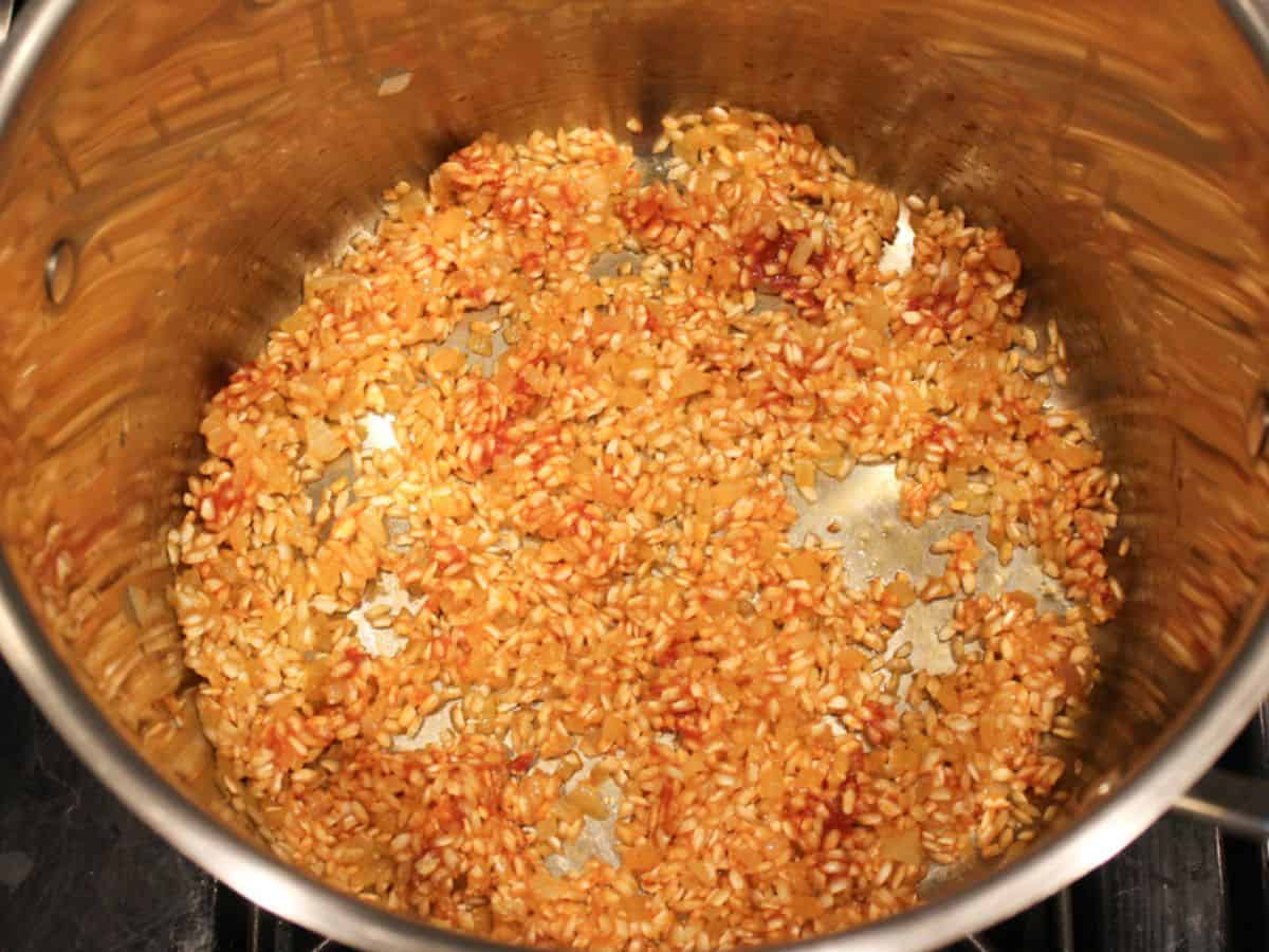 Onions, arborio rice, and tomato paste are sauteed in the pot.