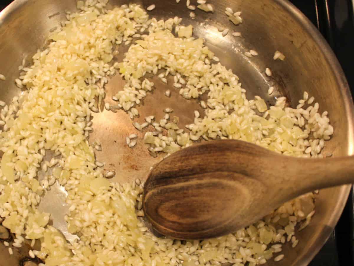 The process of toasting of Arborio rice in a skillet.