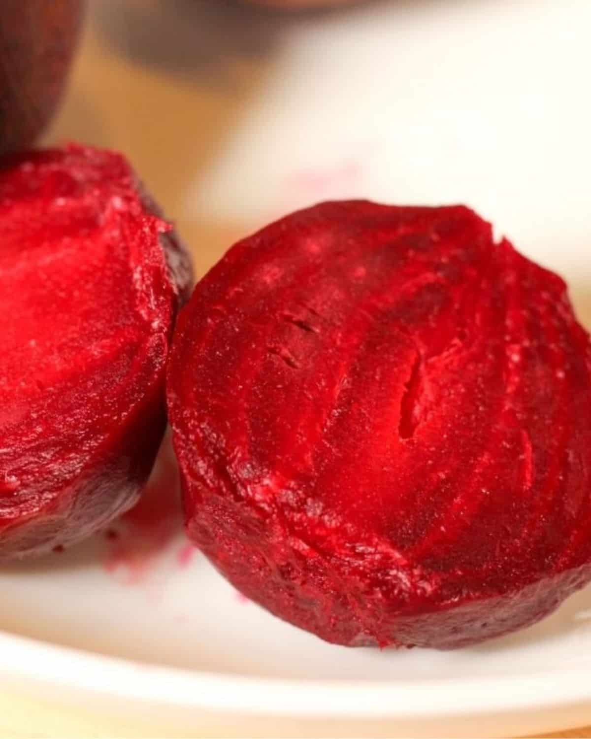 Boiled beet cut in half showing the bright red color inside.