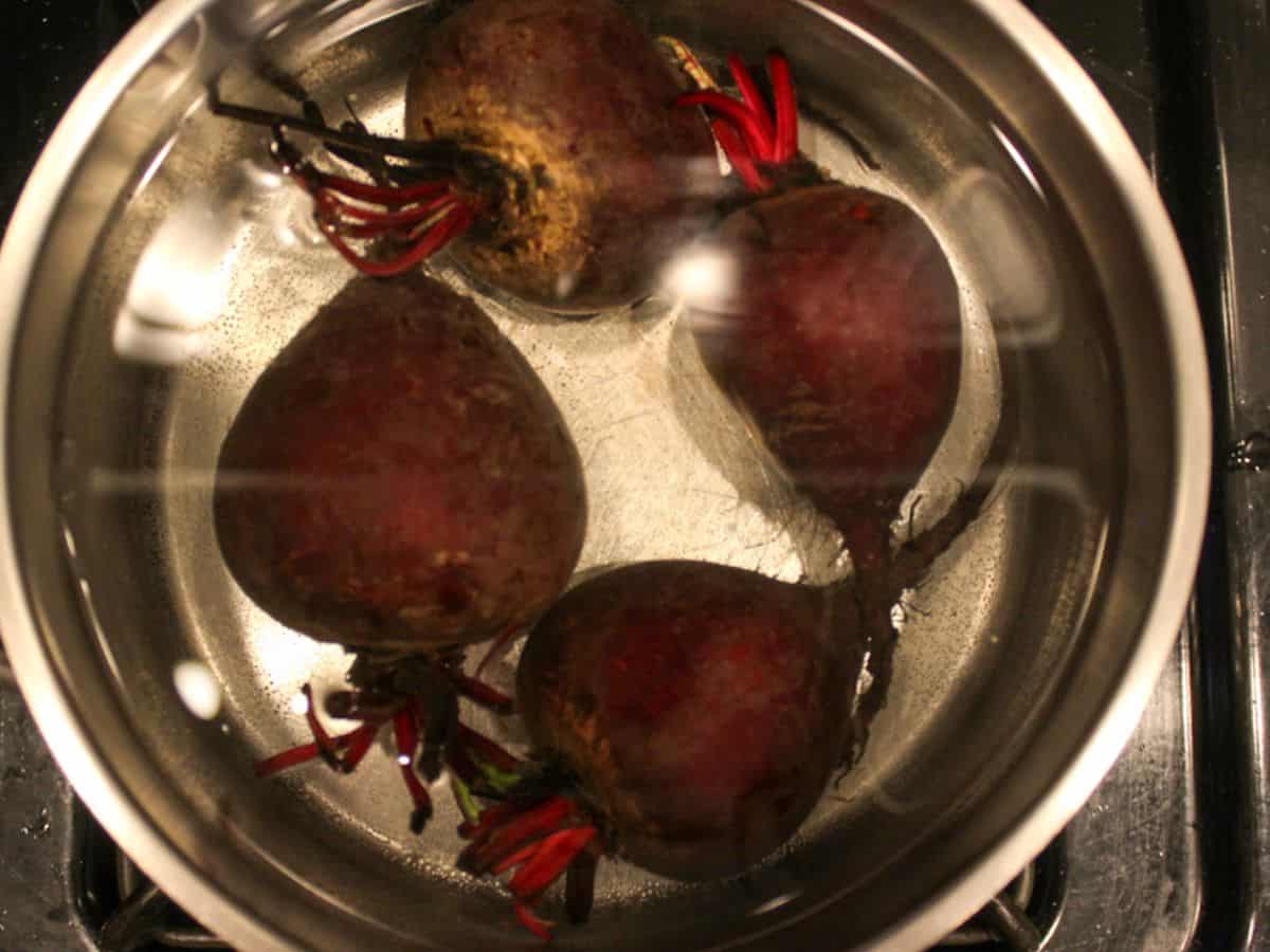 A pot with whole beets covered in water.