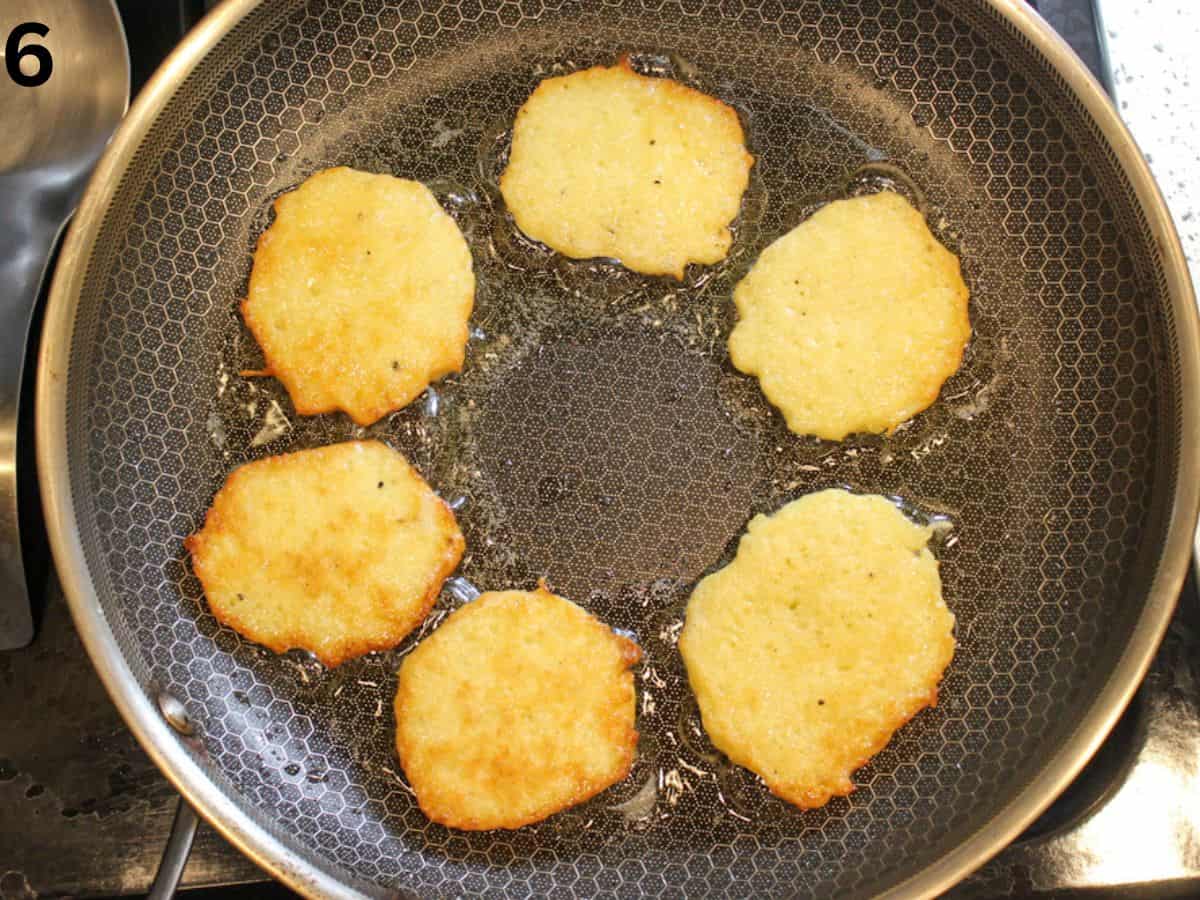 Flipped golden brown potato pancakes in a frying pan.