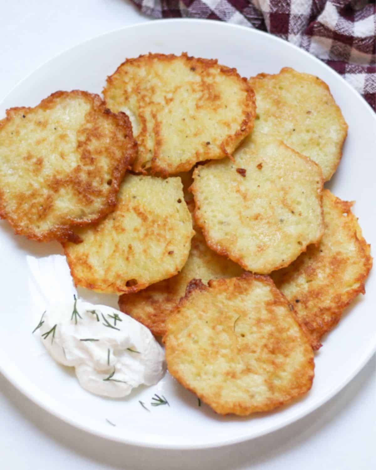 Deruny potato pancakes on a white place served with a dollop of sour cream.