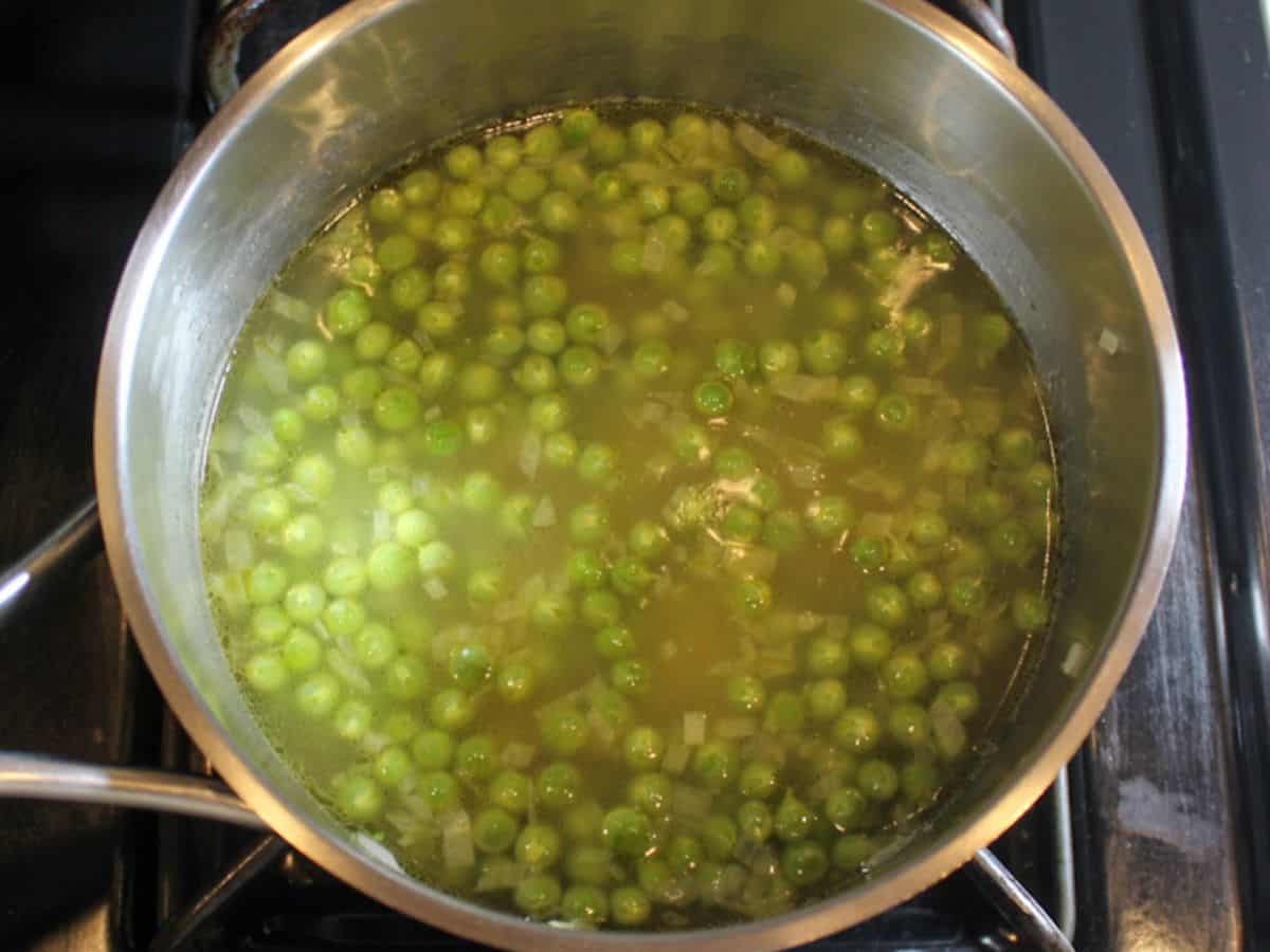 Broth added to the pot with pasta and peas.