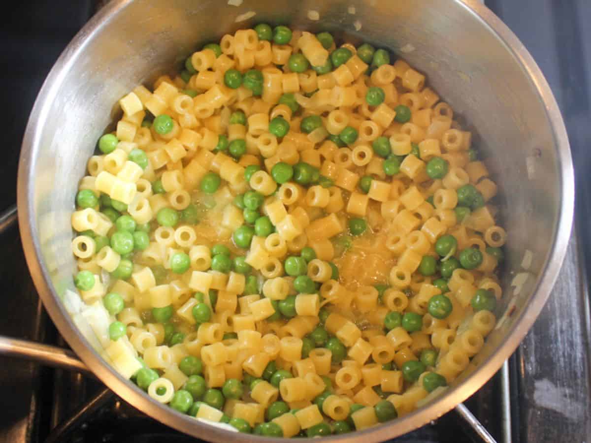Cooked pasta and peas in a stainless steel pot.
