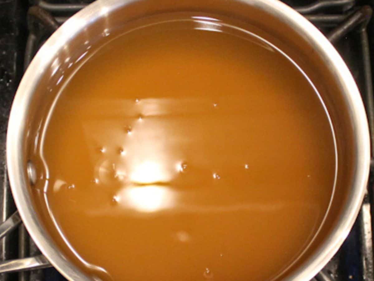 Orange broth is in a stainless steel saucepan.