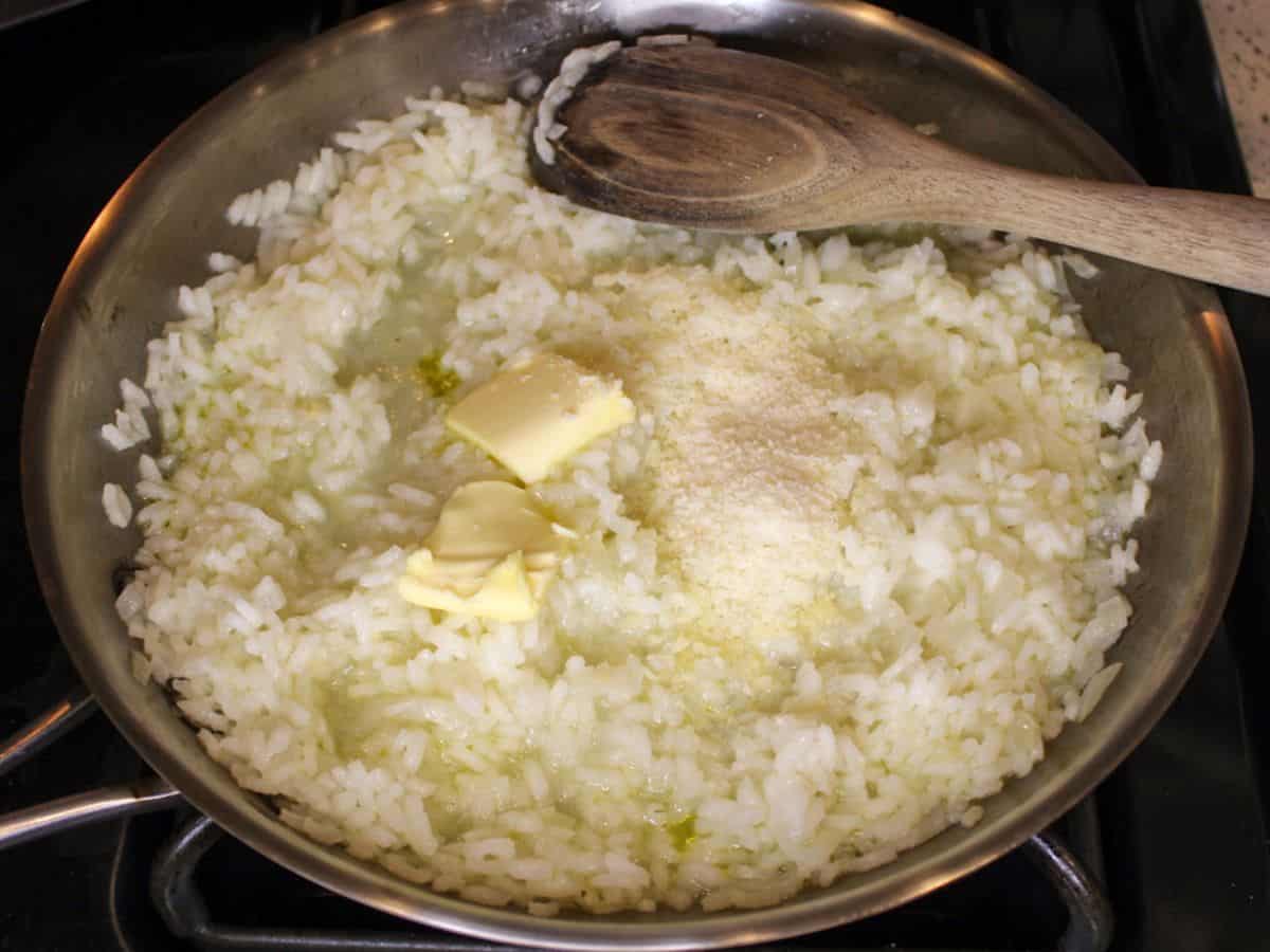 Butter and grated Parmesan added to the cooked risotto in a pan,