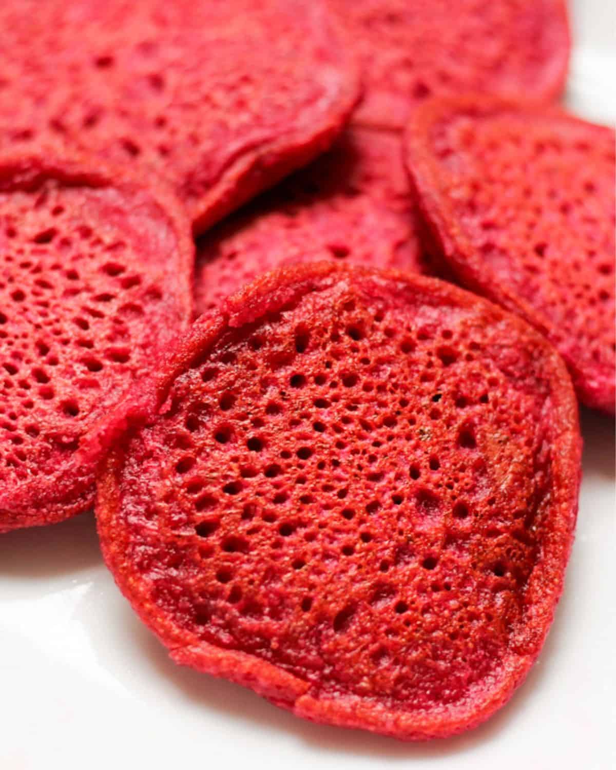 Pink beet pancakes piled on a white plate.