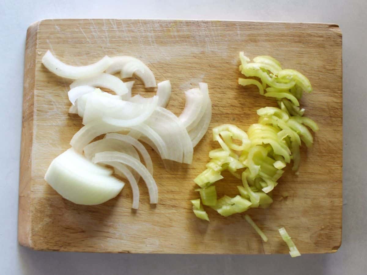 Thinly sliced onion and green pepper on a cutting board.