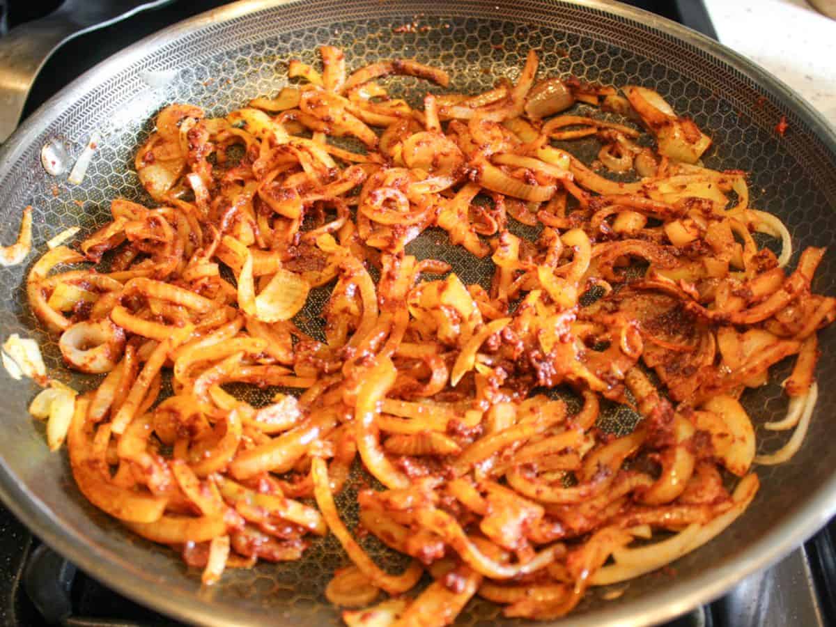 Paprika spice and tomato paste added to the skillet and making the vegetables look red.