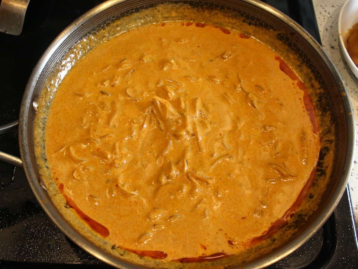 Orange paprika sauce in a skillet palced on a stove top.