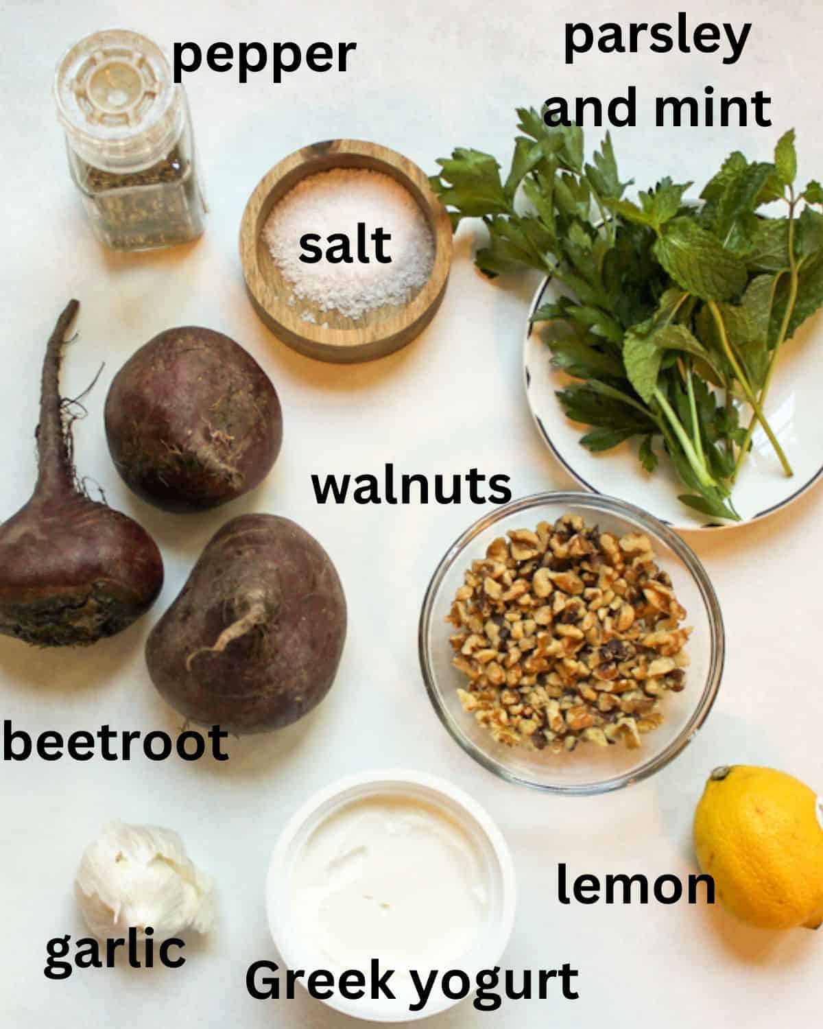 Salad recipe ingredients on a white background labeled as pepper, salt, parsley, mint, beetroot, walnuts, garlic, yogurt, lemon.