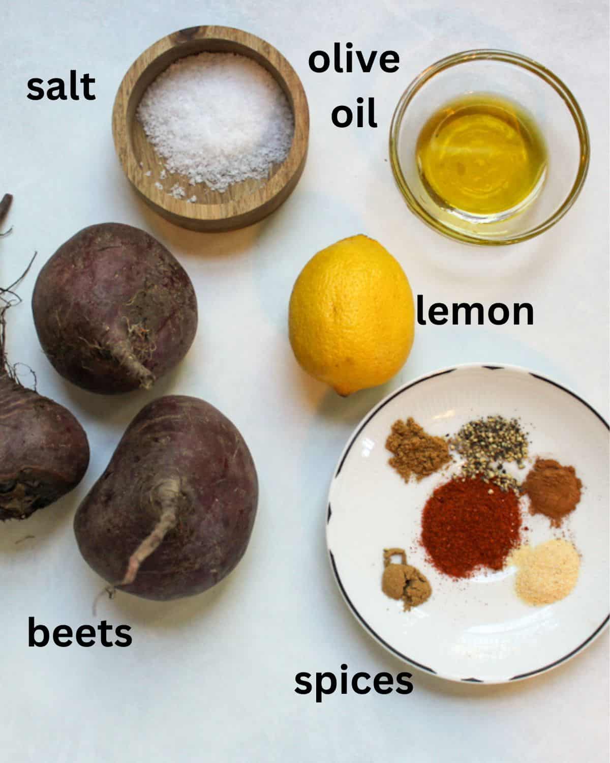 Recipe ingredients from on a white background labeled from top to bottom as salt, oil, beets, lemon, spices.