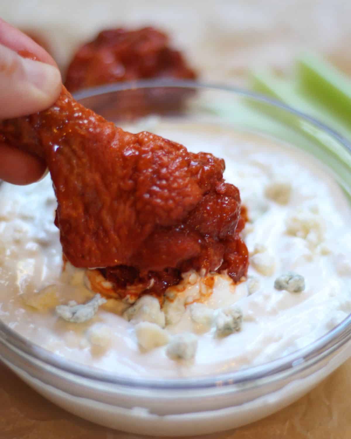 Buffalo chicken wing dipped in a chunky blue cheese dip