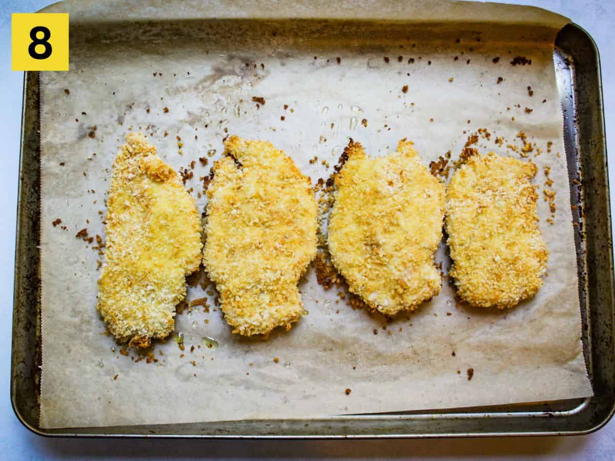 Step eight. Baked breaded cutlets on a baking dish lined with parchment paper.