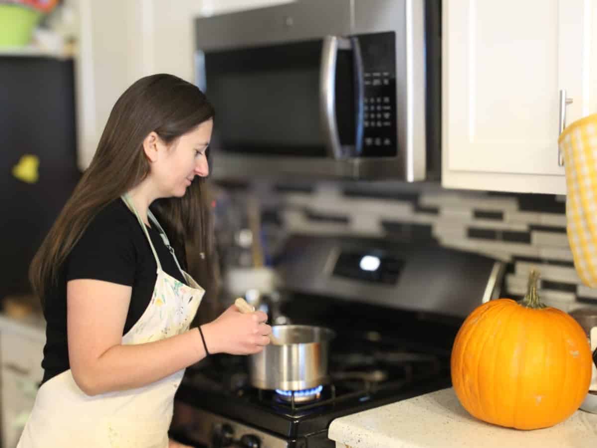 Sava's kitchen female author standing at the stove and stiring the food in a pot.