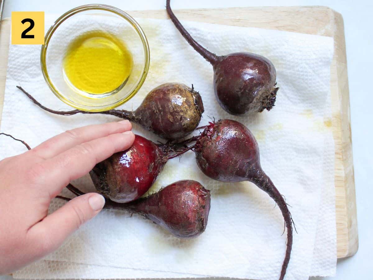 Coating raw whole beets with olive oil.