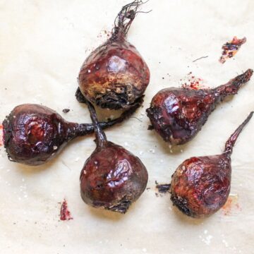 Whole roasted beets on a parchment paper.