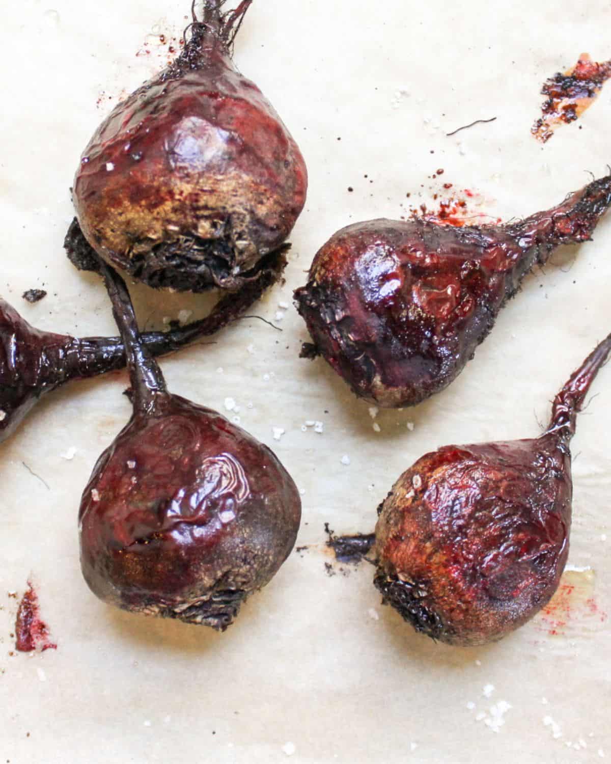 Whole roasted beets on a parchment paper. 